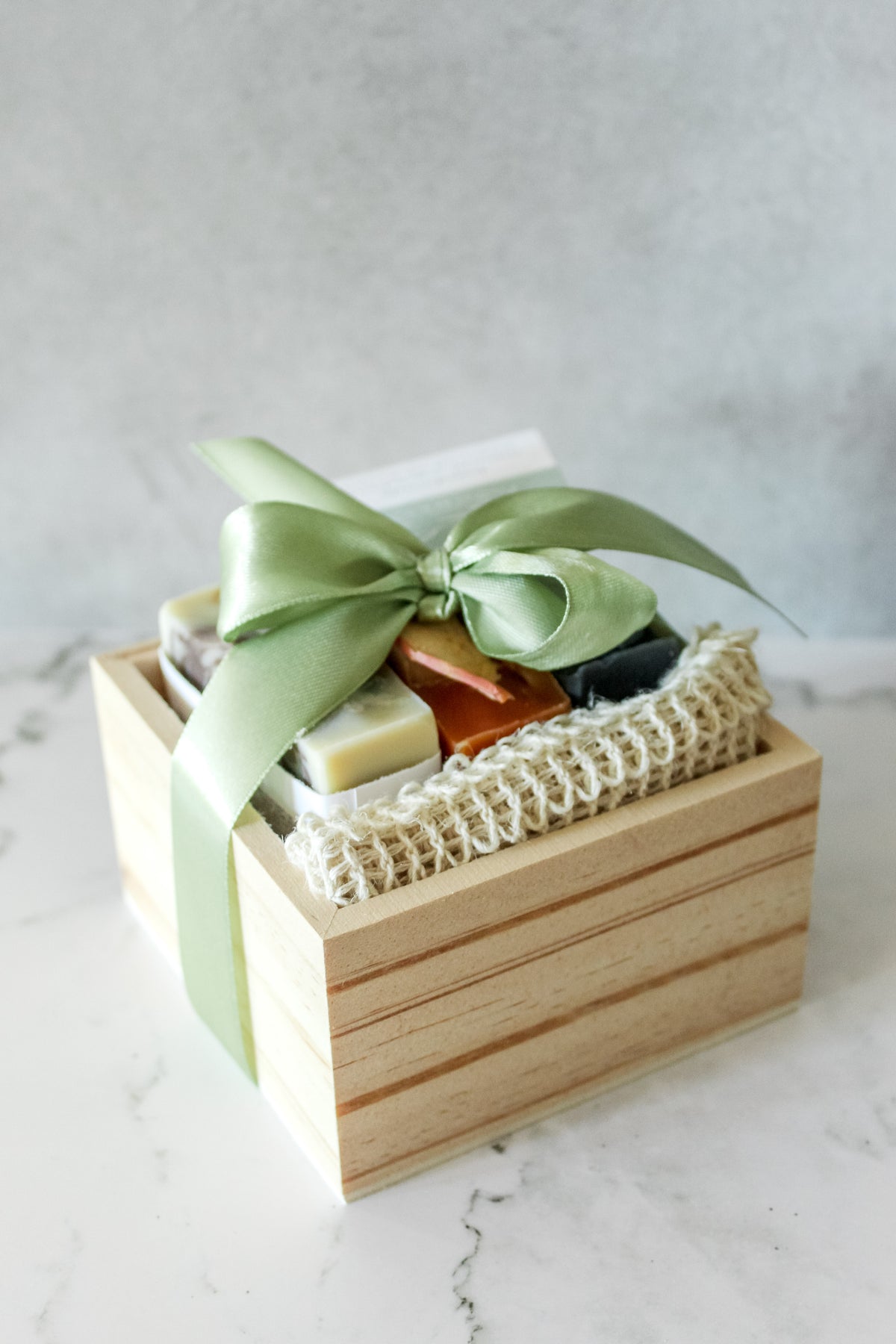 Angled view of the wooden Soap Crate Gift Set tied with a green ribbon bow