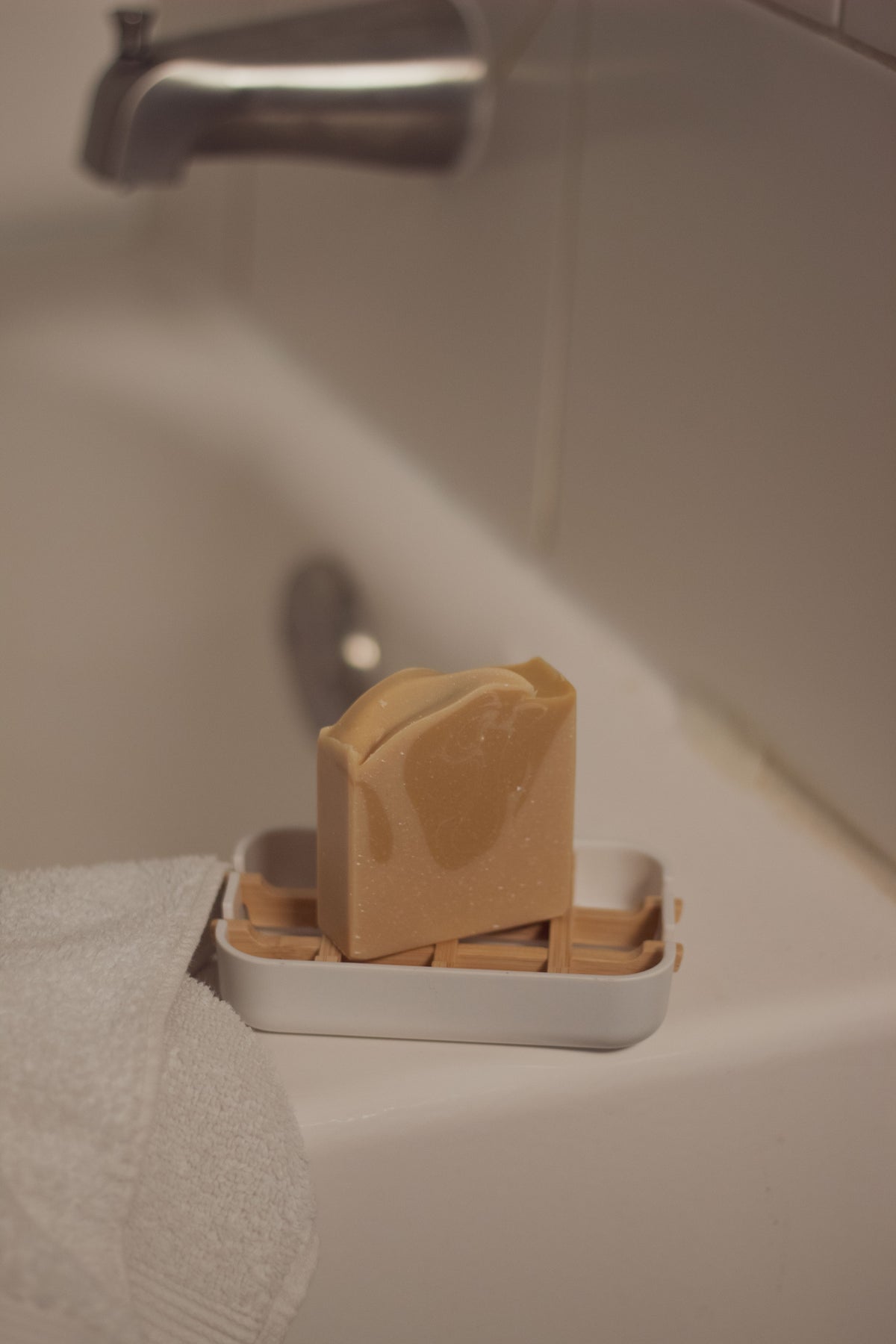 Vanilla Woods bar soap in a dish on a bathroom sink