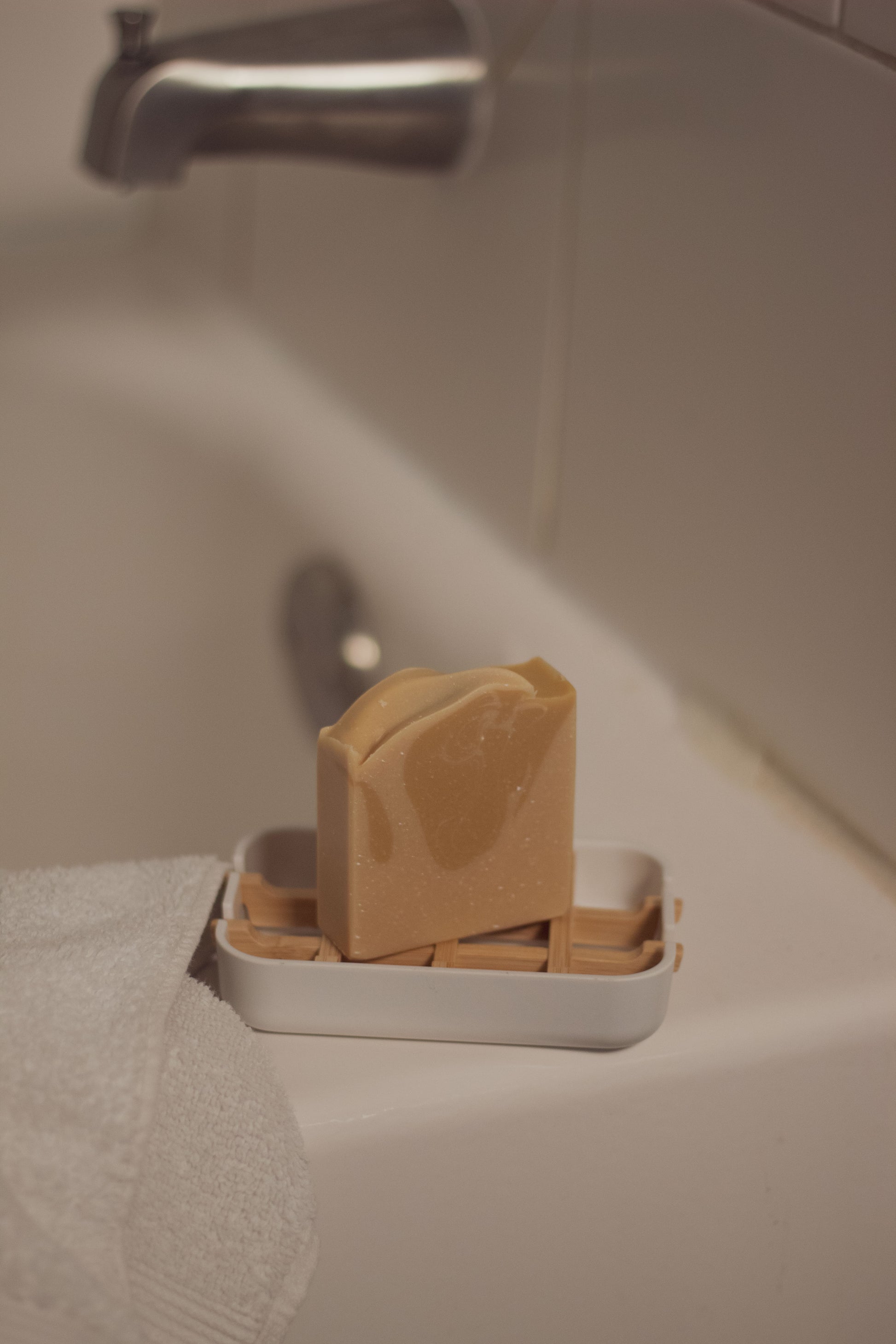 Vanilla Woods bar soap in a dish on a bathroom sink