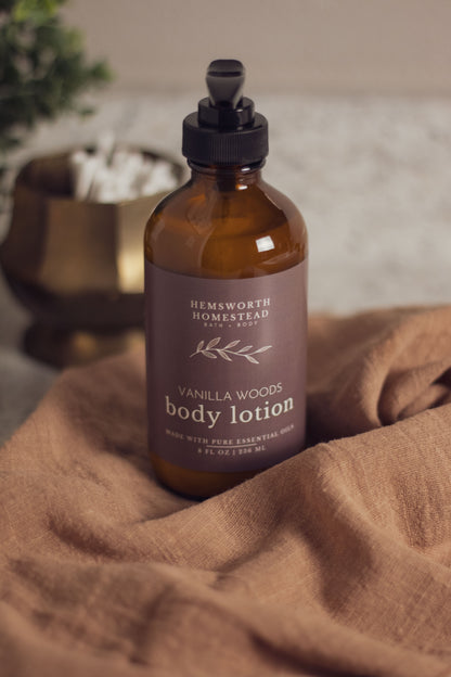 Vanilla Woods body lotion bottle resting on a draped tan fabric background