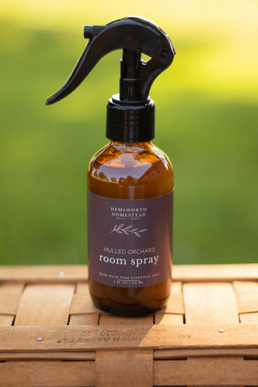 Mulled Orchard room spray bottle with a blurred green outdoor background