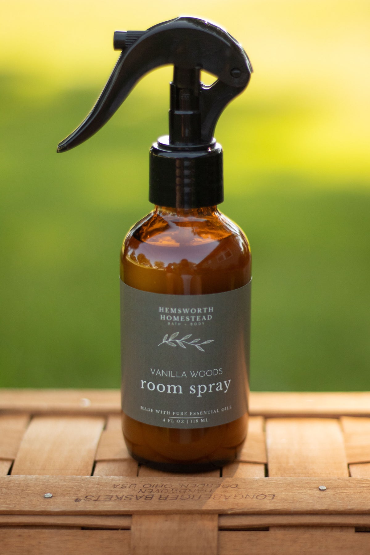 Vanilla Woods room spray bottle with a blurred green outdoor background
