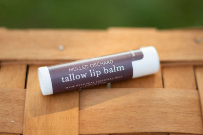 Mulled Orchard tallow lip balm tube lying flat on a wicker basket