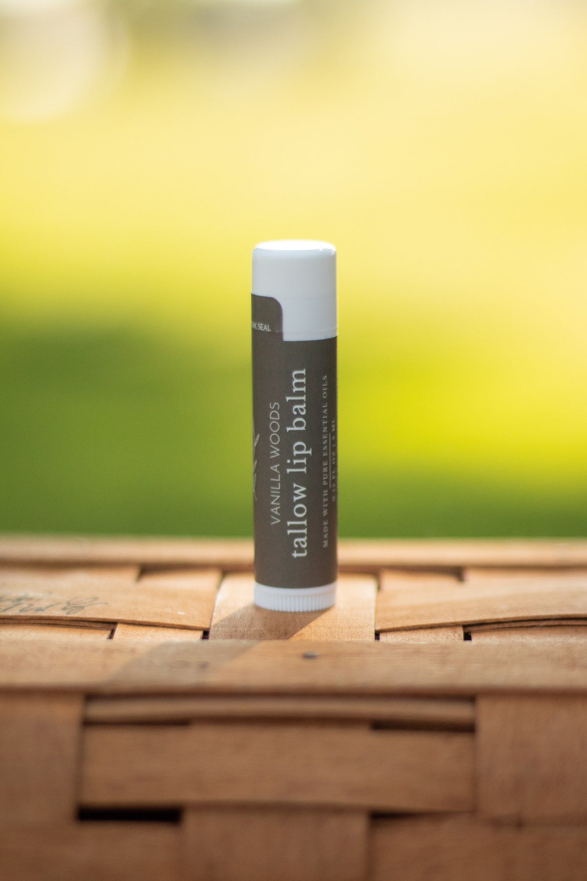 Vanilla Woods tallow lip balm tube standing on a wicker basket