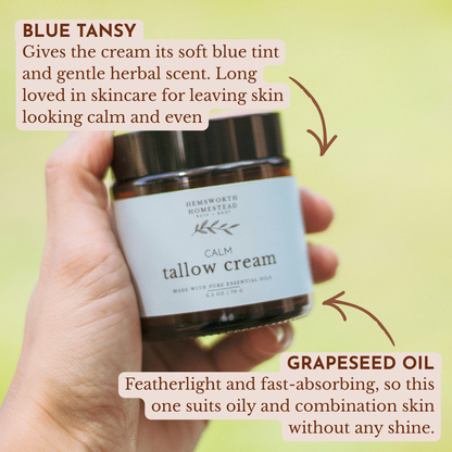 Hand holding a jar of Calm Tallow Cream from Hemsworth Homestead, with ingredient callouts for blue tansy and grapeseed oil